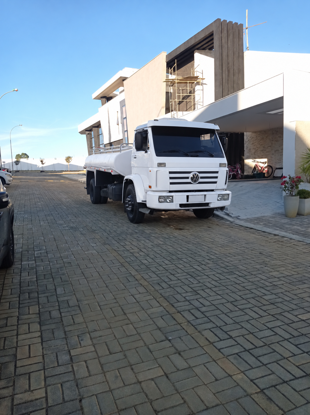 Caminhão-pipa branco da EF Transportes em frente a residência